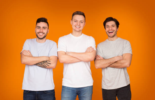 istock Three friends pose together with smiles against a bright orange backdrop during a casual gathering in the afternoon 2174923970