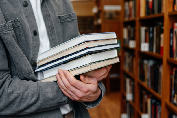 istock young man holds stack of books in hands 2174924092