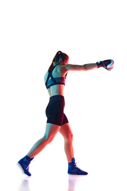 istock Full-length image of young woman in motion, boxing athlete practicing, pouches, training isolated on white studio background in neon light 2174924406