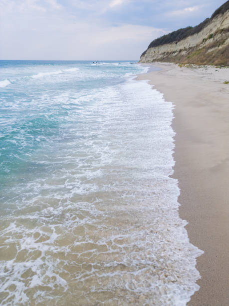 istock A tranquil coastal scene with turquoise waves gently washing onto a sandy beach, bordered by rugged cliffs. Perfect for nature, travel, or seascape photography themes 2174924951