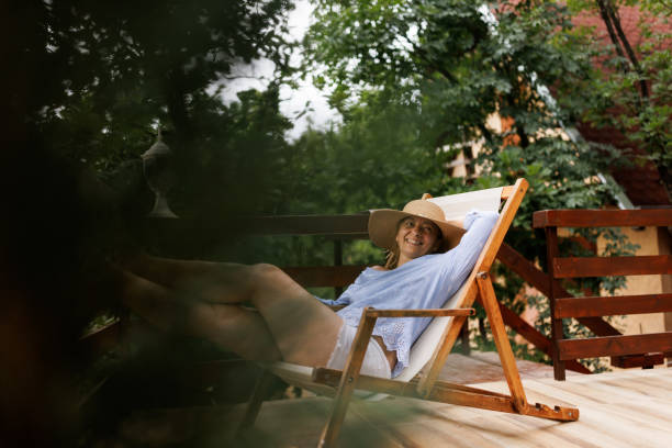 Beautiful mature woman sitting in deckchair and relaxing on balcony