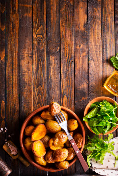 baked potato wedges with sauce on wooden background, top view