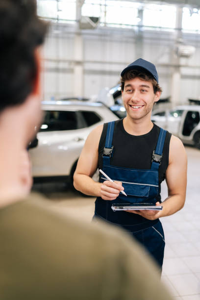 istock Vertical shot from shoulder of unrecognizable man client to smiling mechanic male explaining checklist car maintenance and repair at vehicle repair shop. 2174940910
