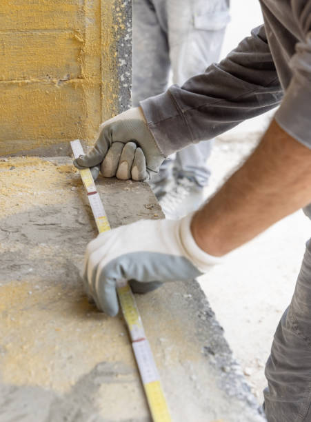 istock Craftsman in gloves measuring a dirty surface with folding ruler. Construction or renovation 2174945387