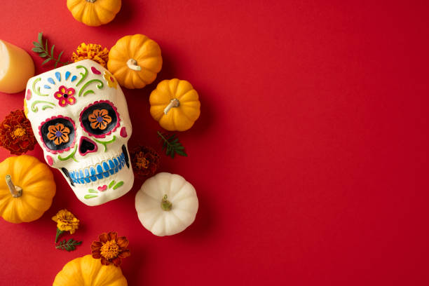 istock Vibrant Day of the Dead setting featuring a decorative sugar skull surrounded by small pumpkins and marigold flowers on a vivid red backdrop 2174946296