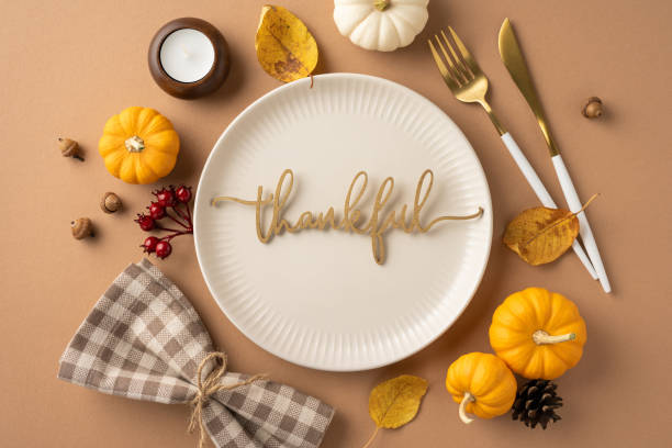 A Thanksgiving theme table setting featuring small pumpkins, thankful message on a plate, and autumn decor elements