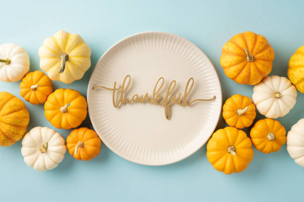 istock A Thanksgiving themed setting showcasing a decorative plate with 'thankful' text surrounded by small pumpkins, symbolizing gratitude and festivity 2174946305