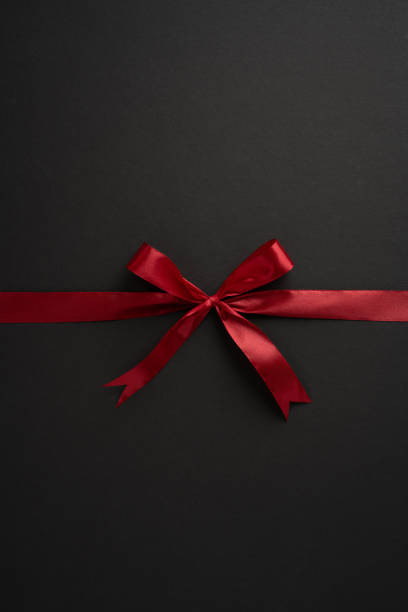 istock Stylish vertical red ribbon bow elegantly tied on a dark background, perfect for gift wrapping, celebrations, and holiday themes 2174946338
