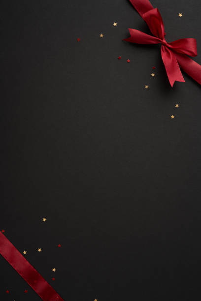 istock A striking vertical composition featuring a luxurious red ribbon and bow on a dark background, adorned with small star-shaped confetti, perfect for holiday or special occasion design themes 2174946350