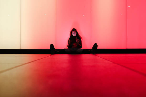 istock Young woman using digital tablet sitting on floor with colorful background 2174949757