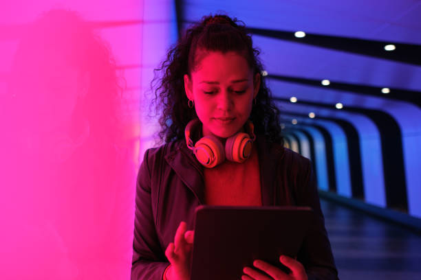 istock Young woman using tablet in neon tunnel at night 2174950598