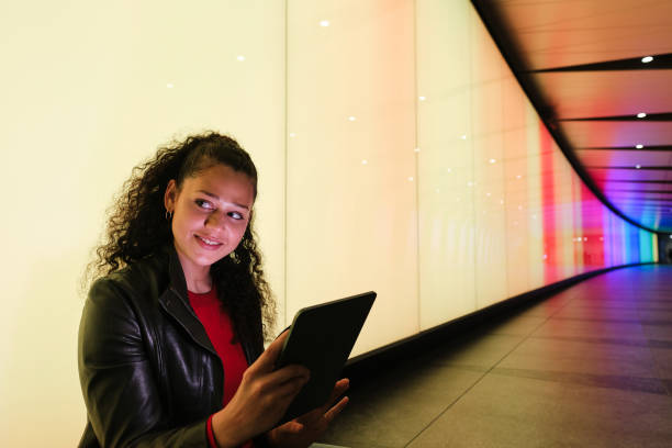 istock Young woman is using tablet and sitting in colorful tunnel 2174951990