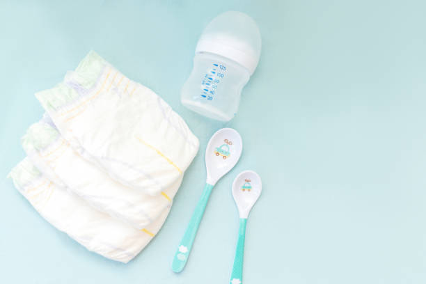 istock Baby's stuff with copy space. diapers with bottle for milk and spoons on blue background. Newborn, infant, baby shower gifts, healthcare concept 2174954302
