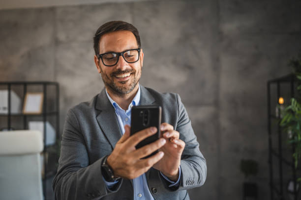 istock confident businessman use mobile phone and smile in modern office 2174991056