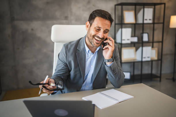 istock cheerful businessman talk on mobile phone and smile in modern office 2174992705