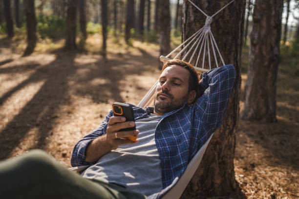 istock Adult man lying down and use mobile phone in hammock 2175001823
