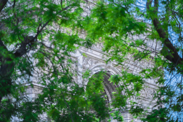 White Arc de Triomphe in Paris France Covered by Tree Branches and Green Leaves