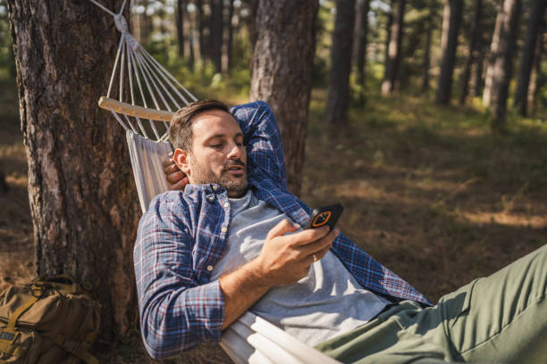 istock Adult man lying down and use mobile phone in hammock 2175007173