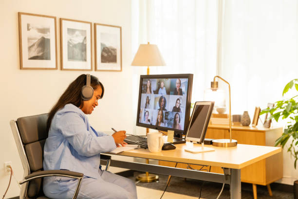 istock Mid adult female smiles while taking notes during her online class after work 2175034806