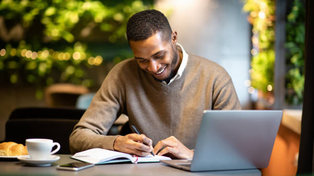 istock Black man writing in notebook sitting at cafe 2175035745