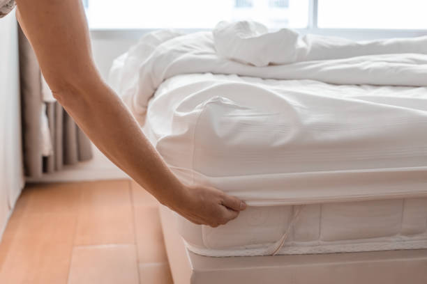 istock A woman makes a bed in a bedroom, securing a white fitted sheet to a polyurethane mattress 2175041969