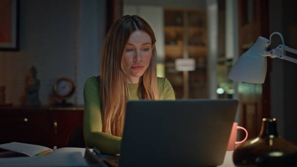 istock Online student studying late evening looking laptop. Woman freelancer working 2175050554