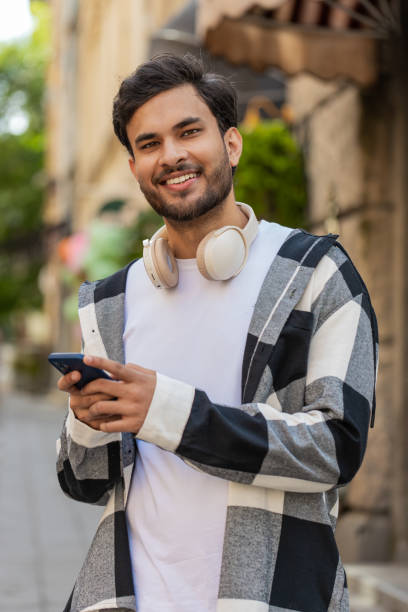 istock Indian man using smartphone typing text messages in social media application online on city street 2175050715