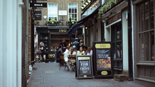 London, England, Apr 30 2023: Carnaby Street side street view with some people sitting out in the pubs and restaurants