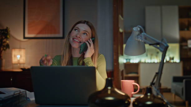 istock Positive remote worker talking mobile phone at desk laptop late evening close up 2175055571