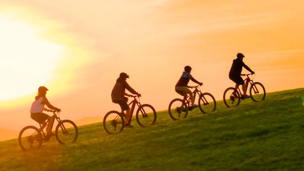 istock AERIAL: Evening sunbeams shine on mountain bikers pedalling up grassy hill. 2175065470
