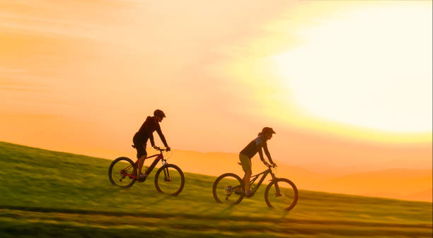 istock AERIAL: Evening sunbeams shine on mountain bikers speeding down grassy hill. 2175065507