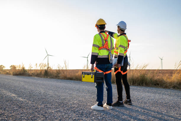 istock Rear view of two technicians man looking at the wind turbines field. Innovation engineer men wearing safety gear, work to develop environmental renewable clean energy outdoors at windmill power farm 2175076303