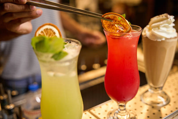 Bartender adding garnishes to colorful cocktails, creating a visually appealing presentation on the bar counter
