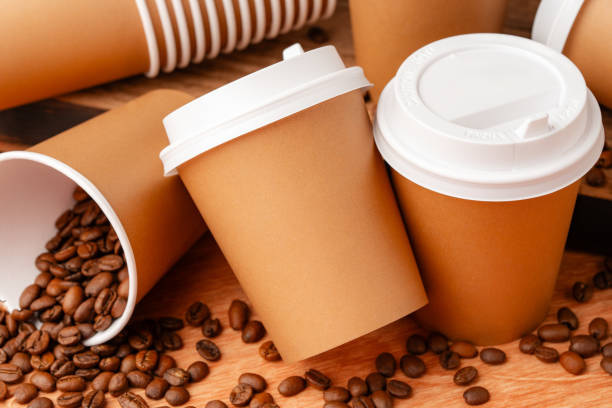 istock Brown disposable coffee cups arranged with coffee beans and a newspaper on a wooden surface in a casual setting 2175082939