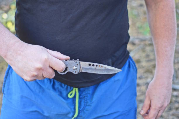 istock one man in black blue clothes holds a gray folding knife 2175086309