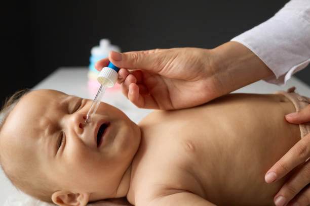 istock Unrecognizable mother using nasal spray for flu treatment clearing nasal congestion ensuring proper care for the sick infant nurse applying nasal drops to unwell baby lying in bed 2175086403