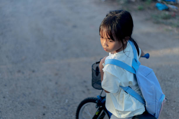 A motorbike stop on street with long shadow on road surface, Vietnamese woman transport children on street, amazing scene from high view at Asia city, Vietnam