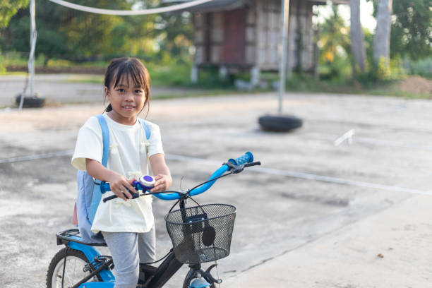 A young girl is sitting on a bicycle with a basket. She is smiling and she is enjoying herself