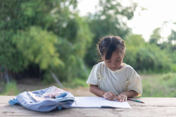istock A young girl is sitting at a table with a backpack next to her 2175087457
