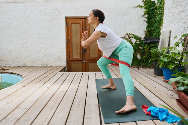 istock Woman practicing yoga on a mat using resistance bands outdoors in a serene patio setting surrounded by plants 2175088045