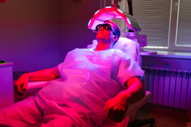 istock Relaxed handsome young man client with hairloss problem having LED light hair photodynamic therapy treatment after hair transplant at clinic. 2175088069