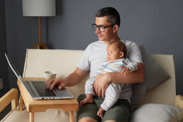istock Freelancer dad typing on keyboard while rocking his newborn baby on couch managing freelance business tasks on computer at home balancing fatherhood and online work 2175117263