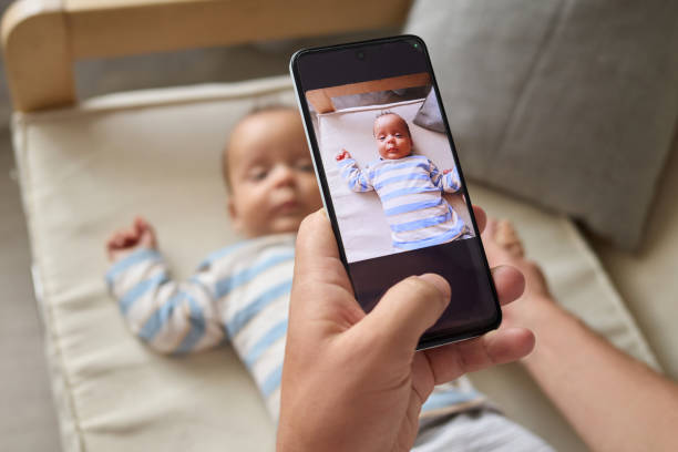 istock Unrecognizable anonymous man sitting on sofa with his infant son capturing cute picture for social networks while enjoying the moments of parenthood at home 2175117292