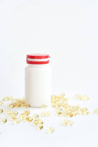 istock Red cap bottle with white label and scattered yellow capsules isolated on clean 2175117381