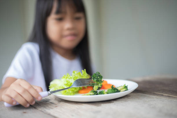 istock A girl is eating broccoli and carrots on a plate 2175117457