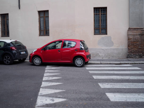 Cremona, Italy August 31st 2024 A red car illegally parked in a european city street, blocking a pedestrian crossing and posing a safety hazard