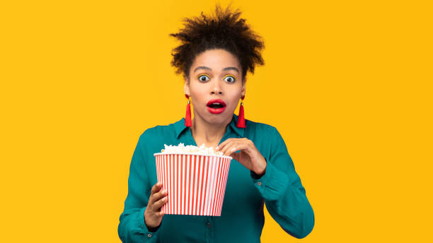 istock Surprised black girl with popcorn staring at camera 2175119110