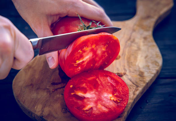 istock Slicing Fresh Tomatoes on a Wooden Cutting Board 2175132743