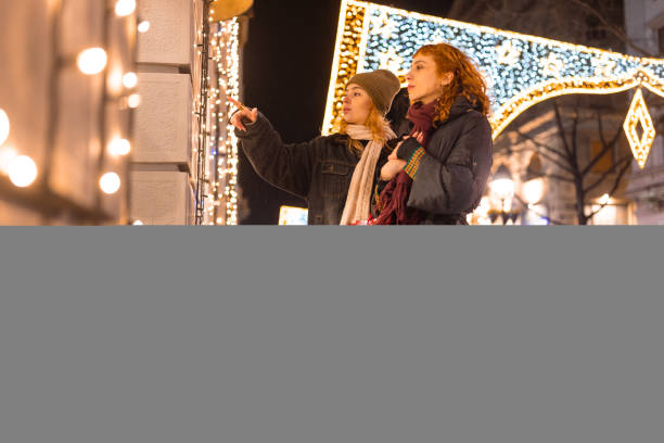 Couple enjoying holiday shopping at night, admiring festive decorations on a city street.