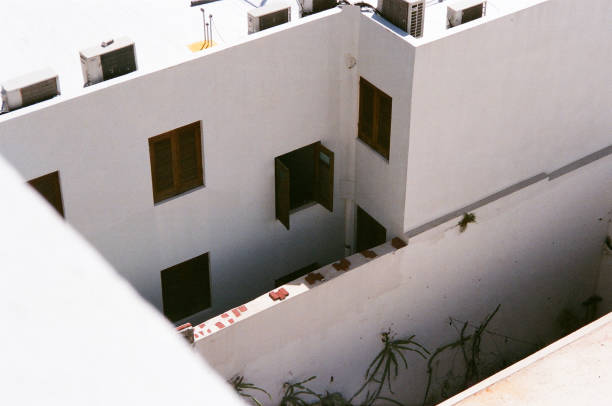 Peering down from above, the photo captures an open wooden window leading into a hidden, quiet courtyard, where natural light filters softly through the space.